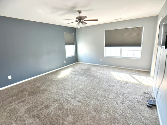 an empty room with windows and a ceiling fan