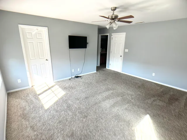 an empty room with fan and windows