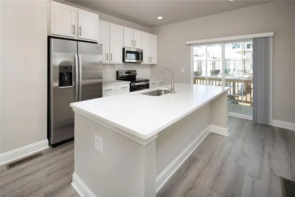 a kitchen with kitchen island a sink appliances and cabinets