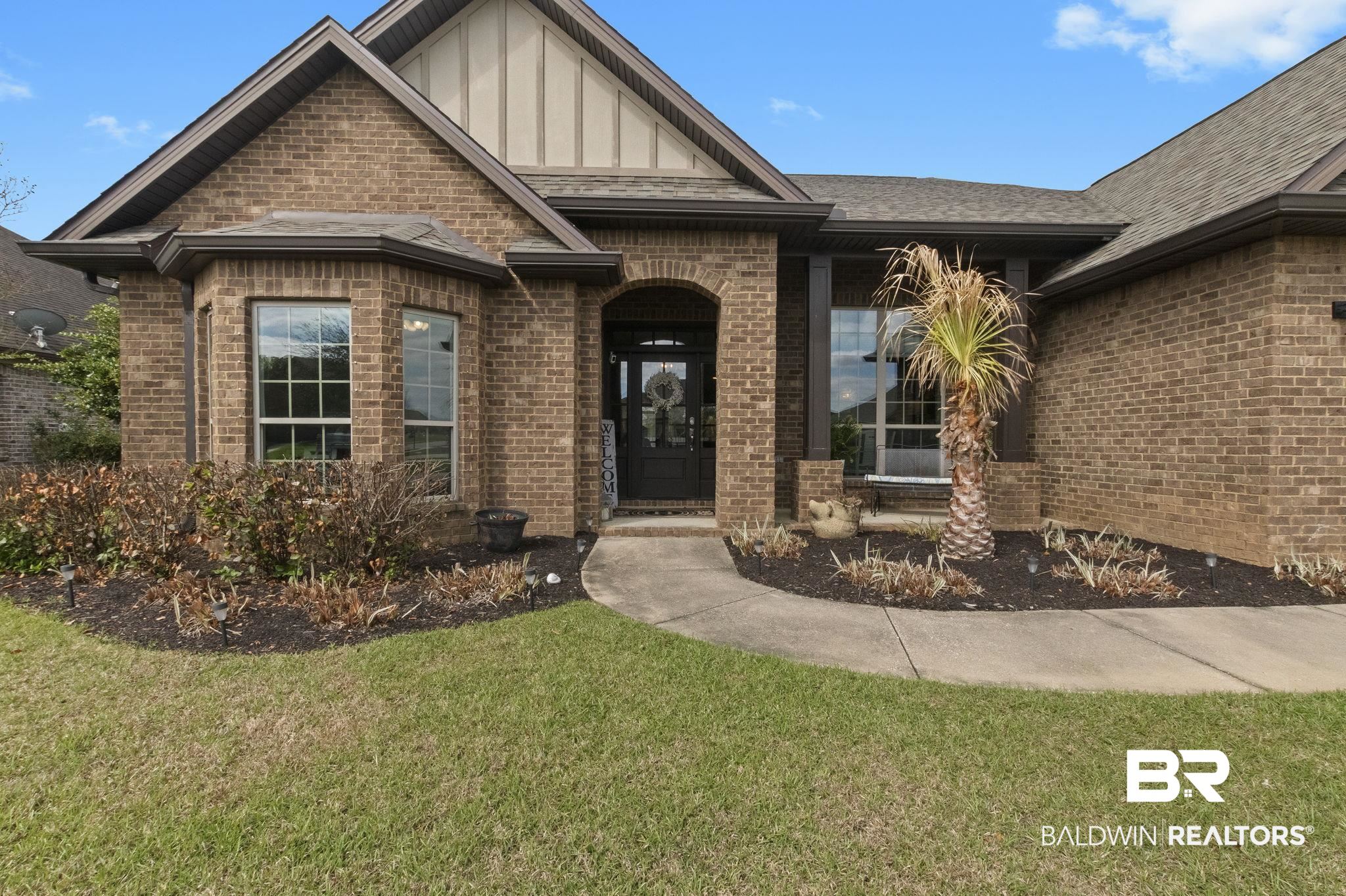 7051 Rocky Rd Loop Gulf Shores, AL 36542 - Photo 2 of 27 View of front of home with brick siding, roof with shingles, and a front lawn