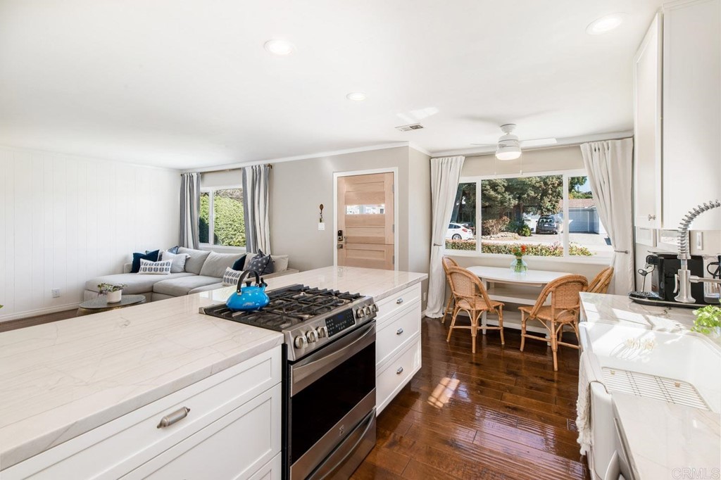 220 Coneflower Street Encinitas, CA 92024 - Photo 5 of 25 a kitchen with stainless steel appliances kitchen island granite countertop a stove a sink a dining table and chairs with wooden floor
