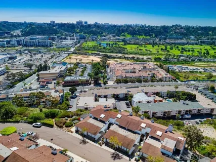 an aerial view of a city with lots of residential buildings ocean and mountain view in back
