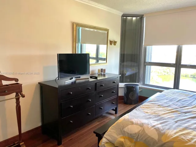 a bedroom with a bed and a flat tv screen next to a window