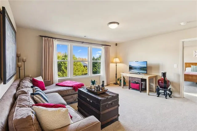 a living room with furniture a flat screen tv and a two large window