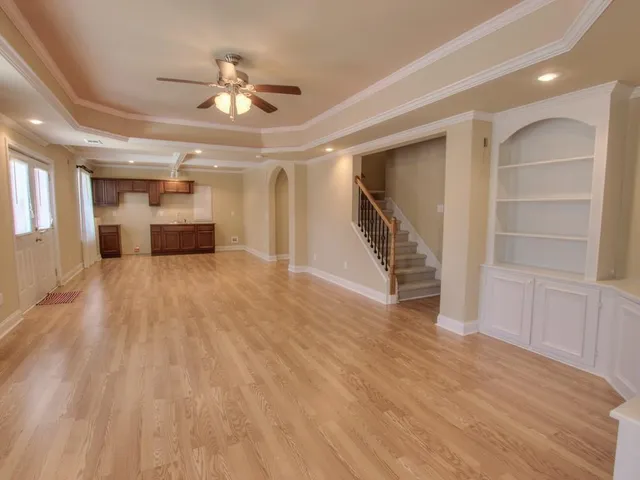 a view of an empty room with wooden floor and a ceiling fan