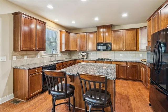 a kitchen with stainless steel appliances granite countertop wooden cabinets a stove top oven a sink and dishwasher