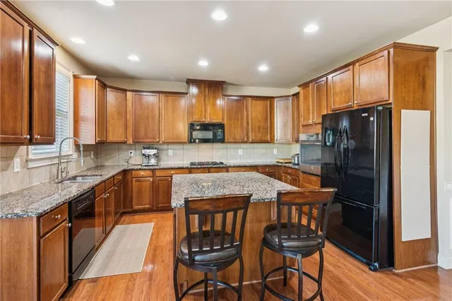 a kitchen with stainless steel appliances granite countertop wooden floor sink stove and refrigerator
