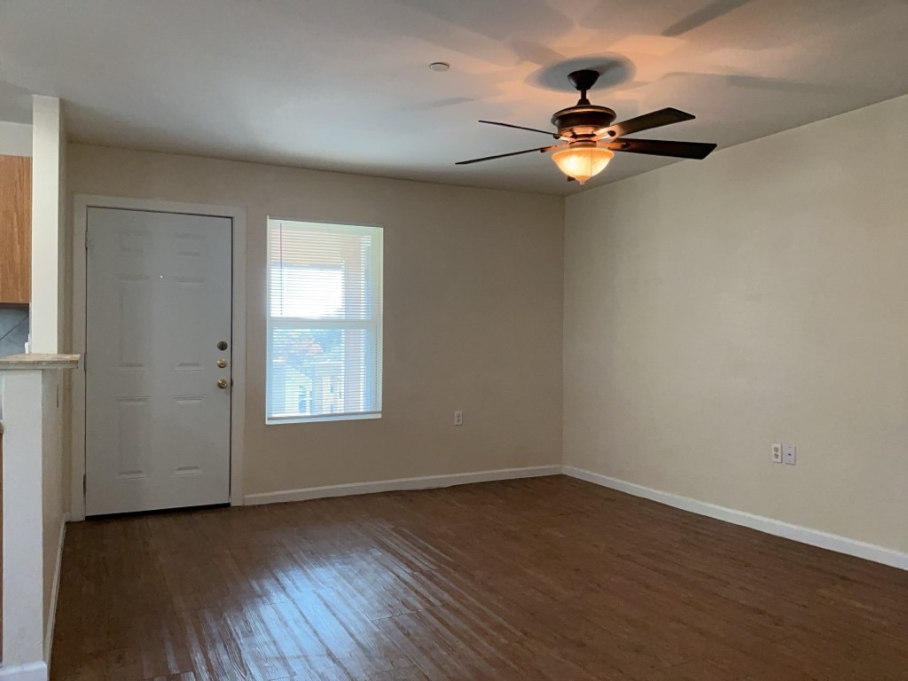 403 Hedgewood Drive, Unit D Georgetown, TX 78628 - Photo 3 of 12 an empty room with wooden floor chandelier fan and windows