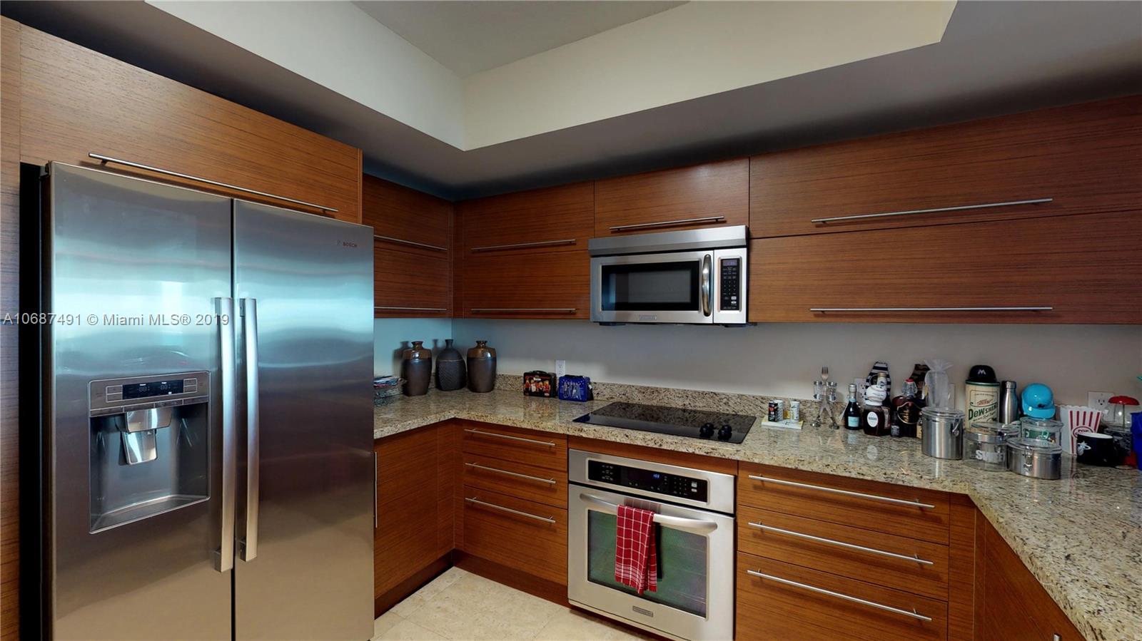 2641 North Flamingo Road, Unit 1401N Plantation, FL 33323 - Photo 21 of 49 a kitchen with stainless steel appliances granite countertop a refrigerator a stove and a sink with wooden floor