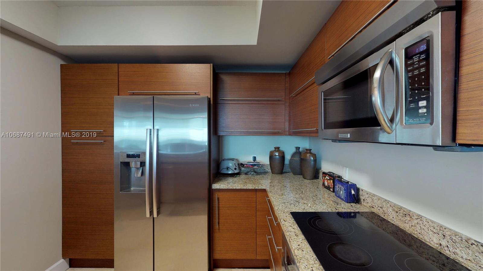 2641 North Flamingo Road, Unit 1401N Plantation, FL 33323 - Photo 25 of 49 a kitchen with stainless steel appliances granite countertop a refrigerator a stove and a sink with wooden floor