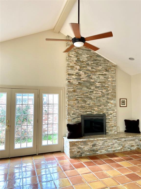 Living room with high ceiling and fireplace with granite and decorative tiles