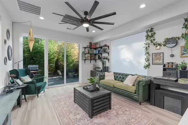 a living room with furniture a ceiling fan and a large window