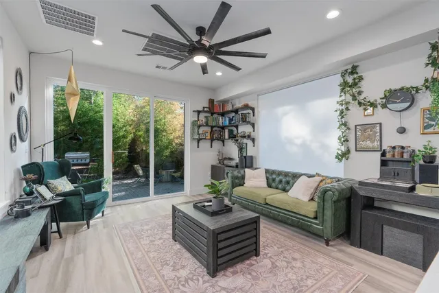 a living room with furniture a ceiling fan and a large window