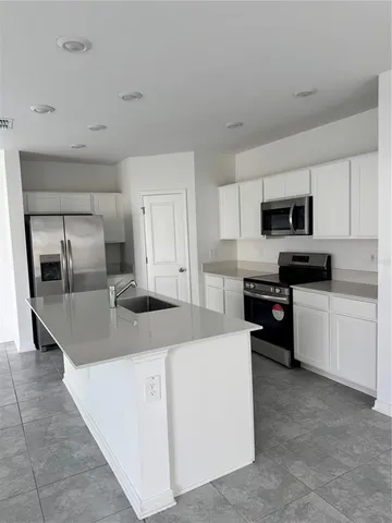 a kitchen with granite countertop a refrigerator and a stove top oven