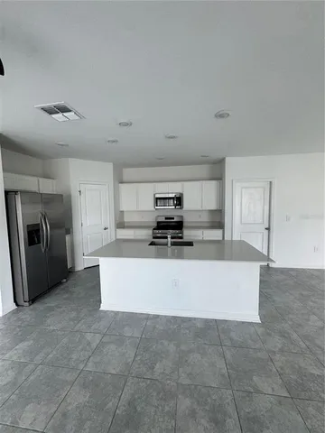 a large white kitchen with a stove a refrigerator a sink and dishwasher