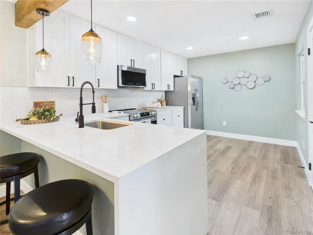 a kitchen with stainless steel appliances a sink a stove a refrigerator cabinets and a dining table