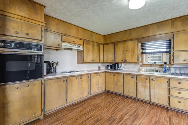 a kitchen with stainless steel appliances granite countertop a sink and cabinets with wooden floor