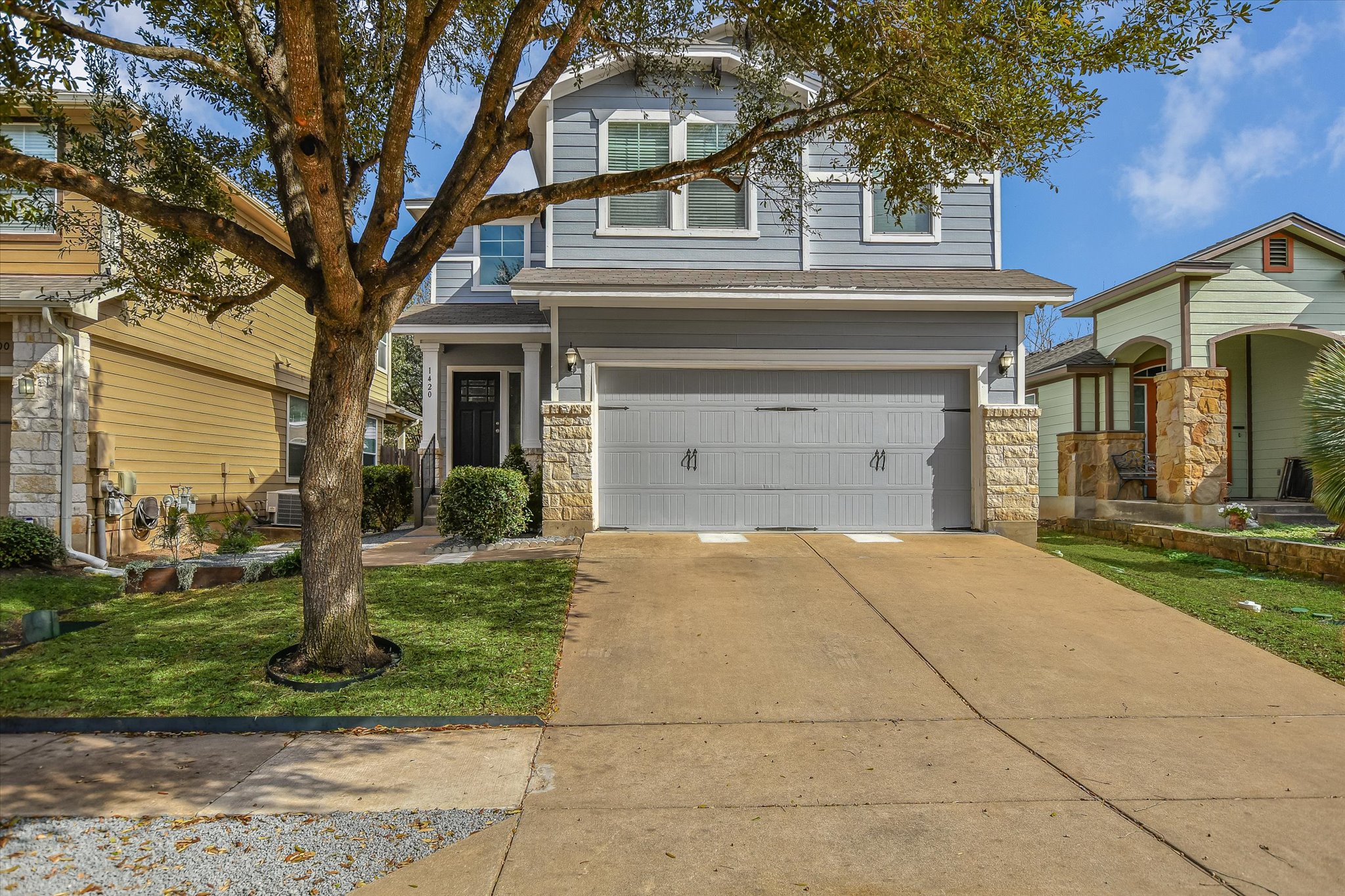 View of front of home with stone siding, concrete driveway, an attached garage, and a front lawn