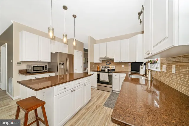 a large kitchen with white cabinets and stainless steel appliances
