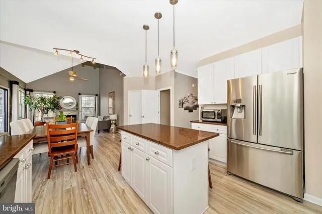 a kitchen with stainless steel appliances granite countertop a refrigerator a sink dishwasher a stove and white countertops with wooden floor