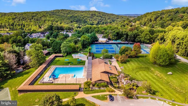 an aerial view of a house with swimming pool large trees and buildings