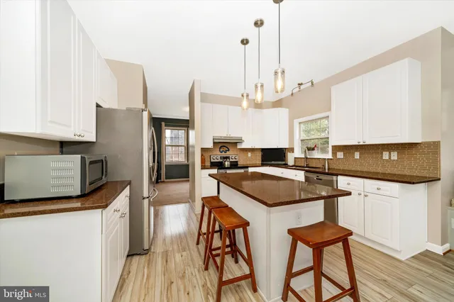 a kitchen with stainless steel appliances a stove a sink a refrigerator a center island and chairs