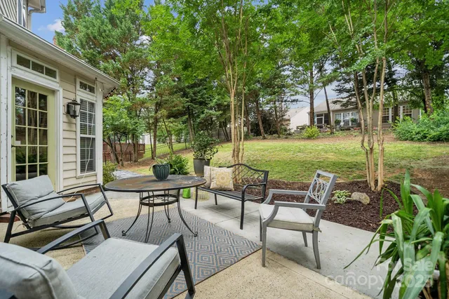 a view of a patio with table and chairs potted plants and a large tree