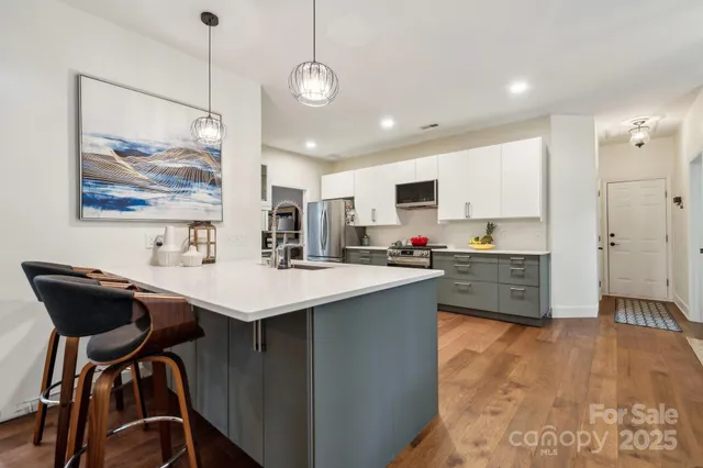 a kitchen with stainless steel appliances kitchen island a chandelier sink and cabinets