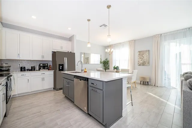 a large white kitchen with lots of counter space a sink appliances and cabinets