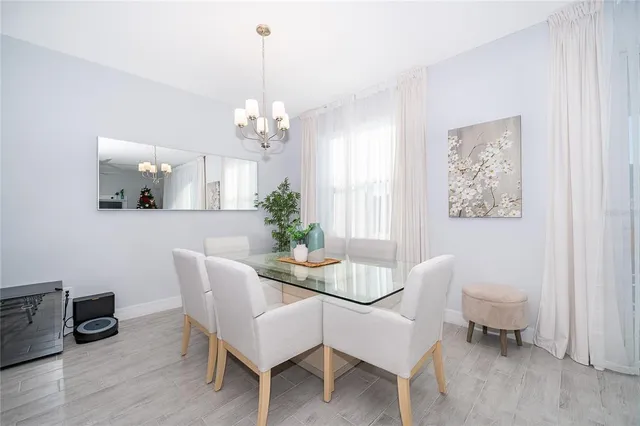 a dining room with wooden floor a chandelier a wooden table and chairs