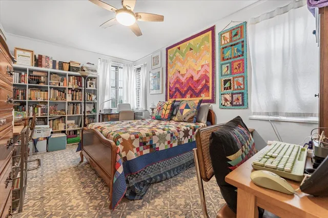 a bedroom with a bed bookshelf and a large window