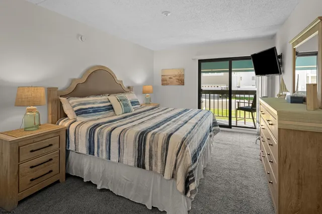 a bedroom with a bed and a flat tv screen on the dresser