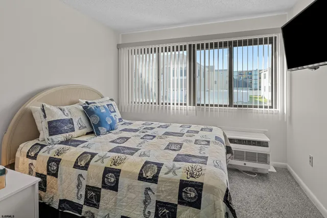 a bedroom with a bed a flat tv screen and a large window