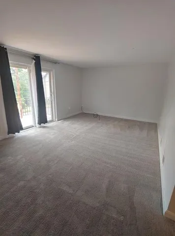 a view of an empty room with window and a kitchen