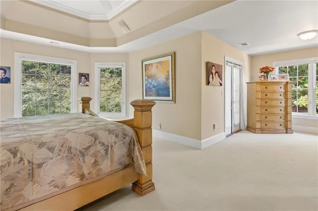 a bed sitting in a spacious bedroom next to a window