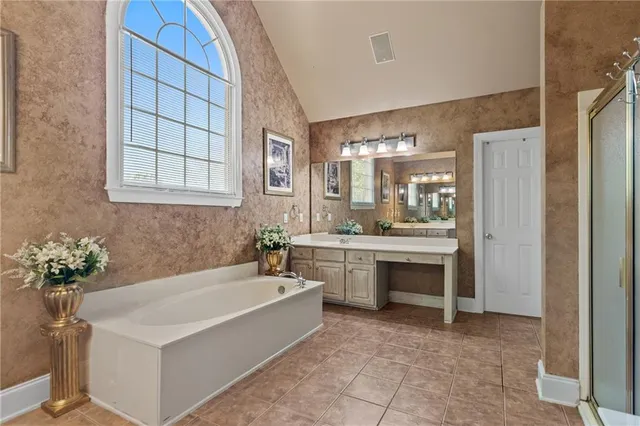 a spacious bathroom with a tub sink and mirror