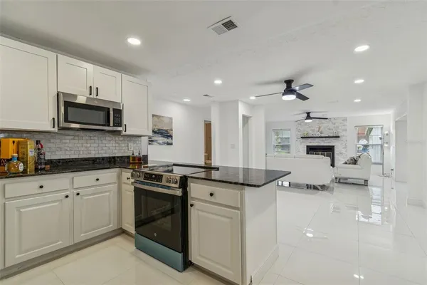 a kitchen with kitchen island granite countertop white cabinets and stainless steel appliances