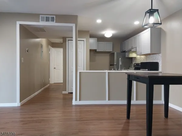 a kitchen with stainless steel appliances granite countertop a refrigerator a sink dishwasher a stove and a refrigerator with wooden floor