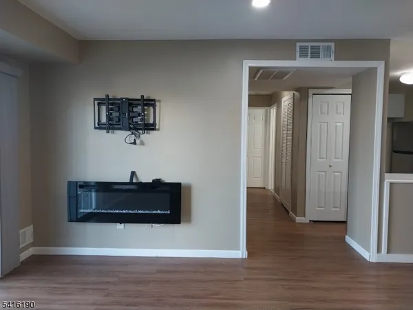 a view of a hallway with wooden floor and cabinet