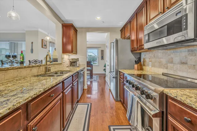 a kitchen with stainless steel appliances granite countertop a kitchen island a stove a sink dishwasher and a refrigerator