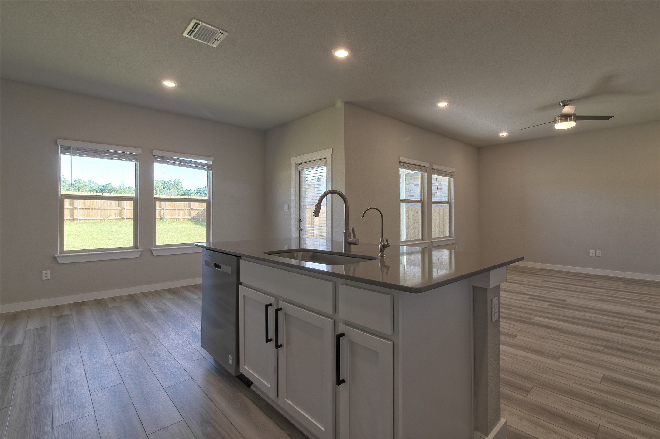 425 Coda Crossing Georgetown, TX 78633 - Photo 35 of 36 Kitchen featuring ceiling fan, light wood finished floors, a center island with sink, dark stone counters, and open floor plan