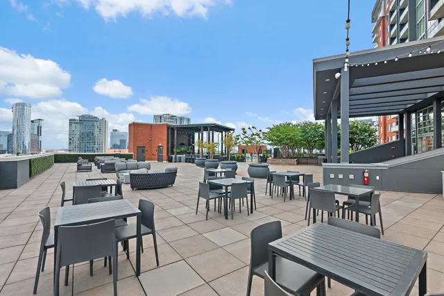 a view of a patio with a dining table and chairs with a fire pit and barbeque grill