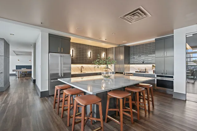 a kitchen with stainless steel appliances granite countertop a dining table chairs and wooden floor