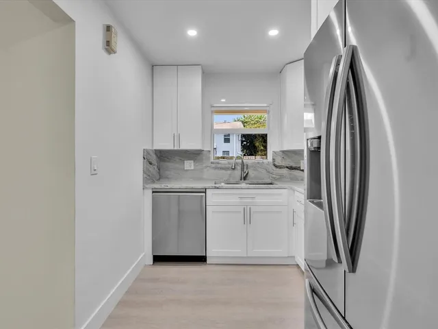 a kitchen with stainless steel appliances granite countertop a refrigerator a sink a stove and white cabinets