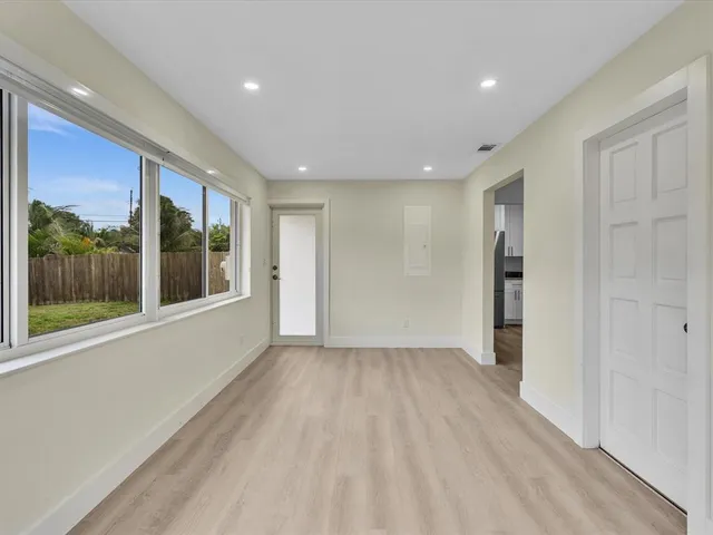a view of an empty room with wooden floor and a window