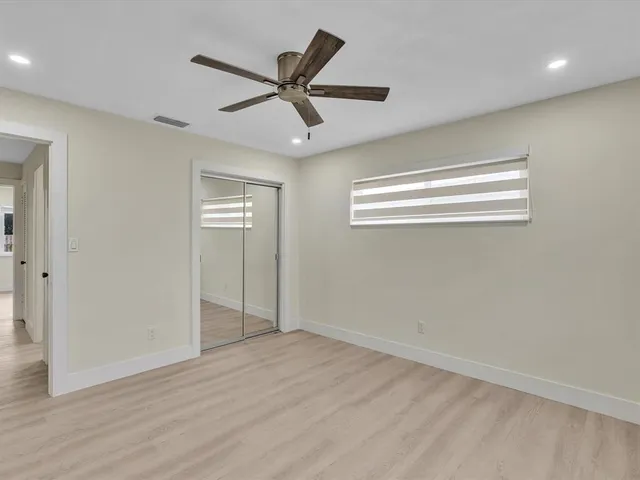 an empty room with wooden floor fan and windows