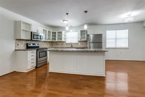 a kitchen with stainless steel appliances granite countertop a sink a stove a refrigerator cabinets and a window