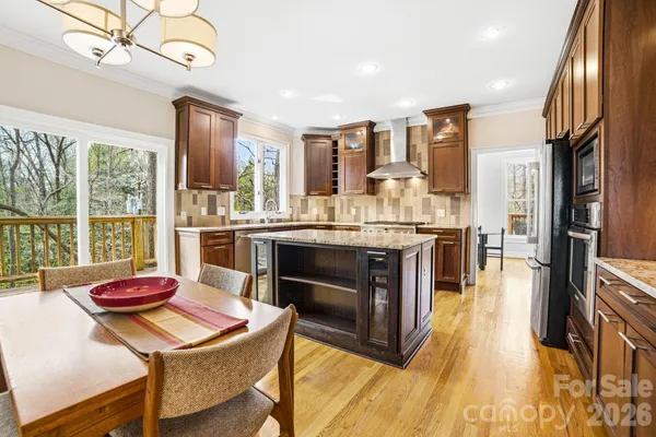 a kitchen with a stove a refrigerator and a dining table with wooden floor