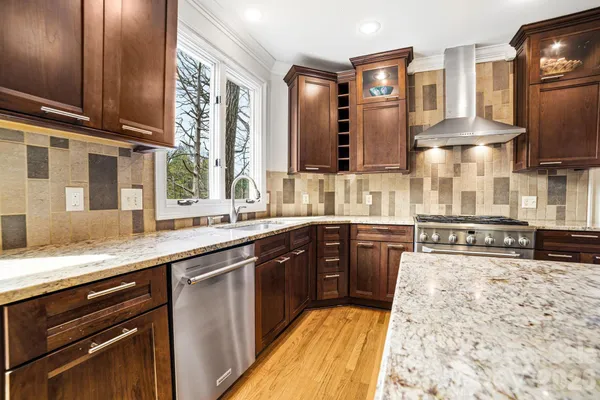 a large kitchen with stainless steel appliances wooden cabinets a stove and a sink