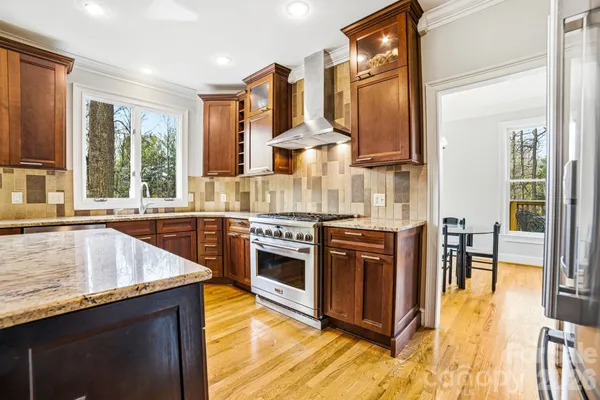 a kitchen with stainless steel appliances granite countertop a sink a stove and a refrigerator